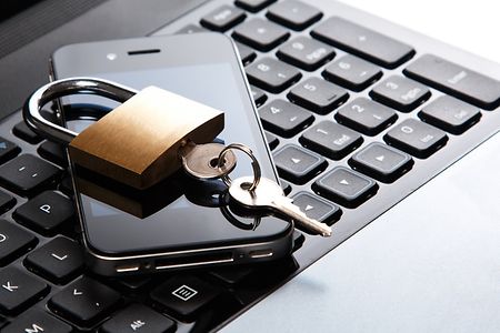 Datenschutz - Ein Smarphone liegt auf einer Tastatur und dar&uuml;ber befindet sich ein Vorh&auml;ngeschloss