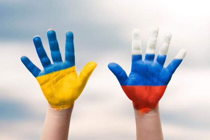 2 Hände - eine eingefärbt wie die ukrainische, die andere wie die russische Flagge