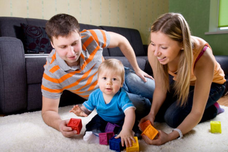 Ein Mann und eine Frau spielen mit einem Baby.