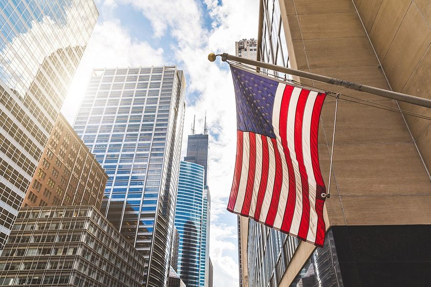 Blitzumfrage der IHK-Arbeitsgemeinschaft Rheinland-Pfalz/Saarland: 100 Tage Trump USA Flagge vor Hochhäusern