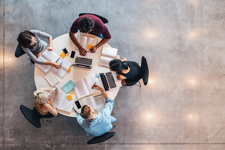 Personen am Tisch sitzend mit Arbeitsmaterial (Perspektive von oben)